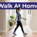 A smiling woman in athletic clothes walking down a bright indoor hallway.
