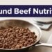 A skillet of cooked ground beef with a kitchen scale and raw portions on a counter.