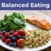 A divided plate of salmon, greens, quinoa, and berries on a wooden table.