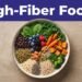 A colorful bowl of beans, grains, berries, greens, vegetables, nuts, and seeds under an indigo banner.