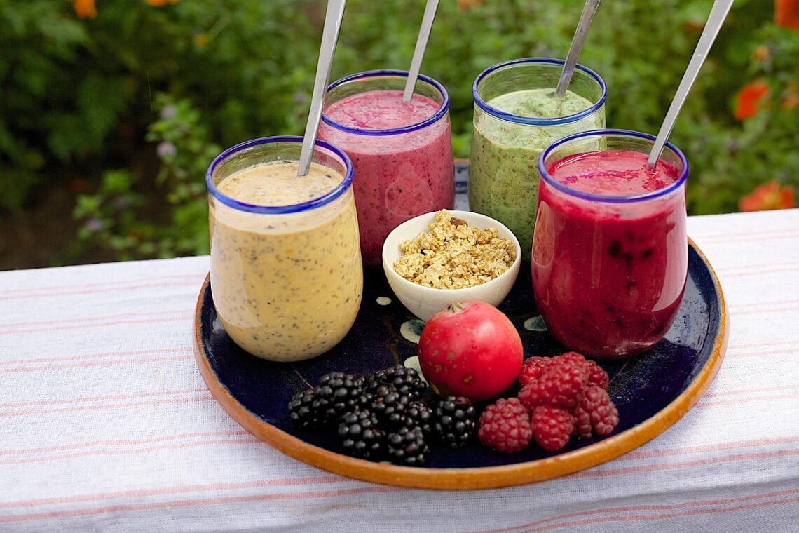 Pink tropical and green superfood smoothies in matching clear cups.