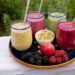 Pink tropical and green superfood smoothies in matching clear cups.