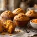 Pumpkin muffins on a cooling rack, with one split open beside pumpkin puree and cinnamon sticks.